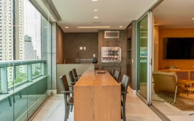 Varanda gourmet com churrasqueira em aço inox e bancada longa com banquetas