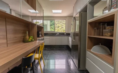 Cozinha com bancada em madeira, geladeira inox e janela panorâmica para a mata