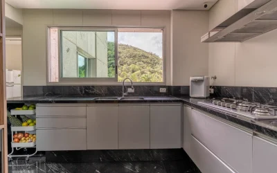 Cozinha com bancada em granito preto, cooktop e vista panorâmica para a serra